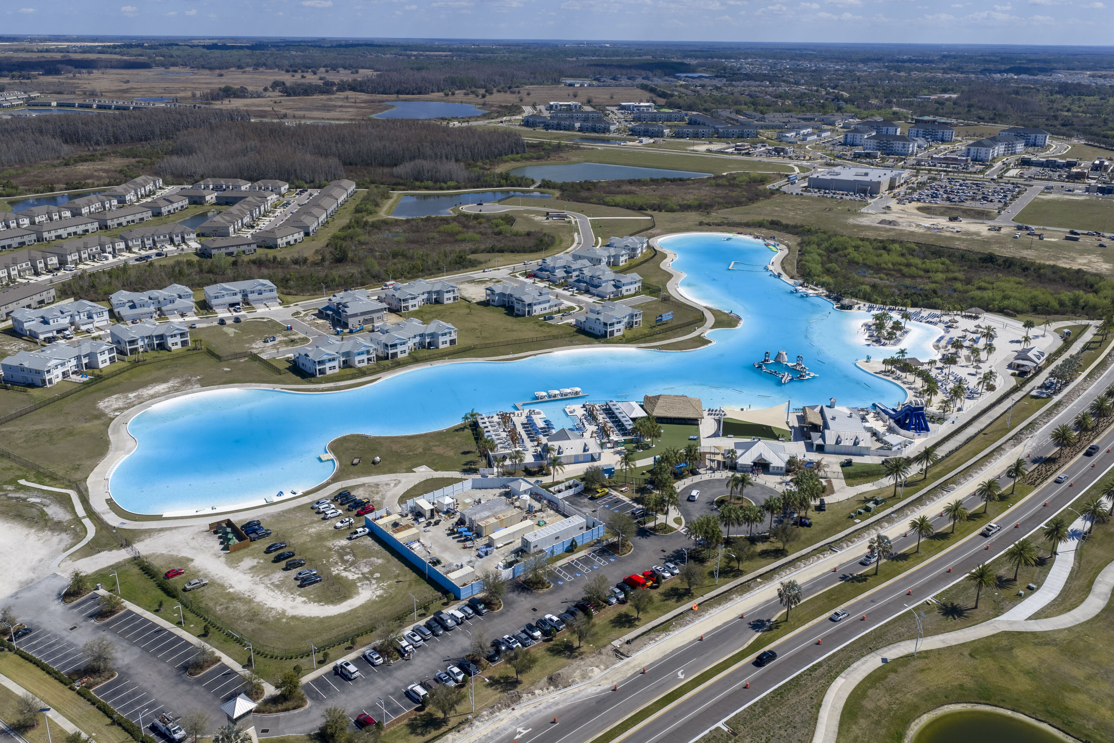 Wesley Chapel, United States - 02 March 2026: Aerial view of Epperson Lagoon featuring turquoise water, modern residential housing, and palm trees under a bright sky.
