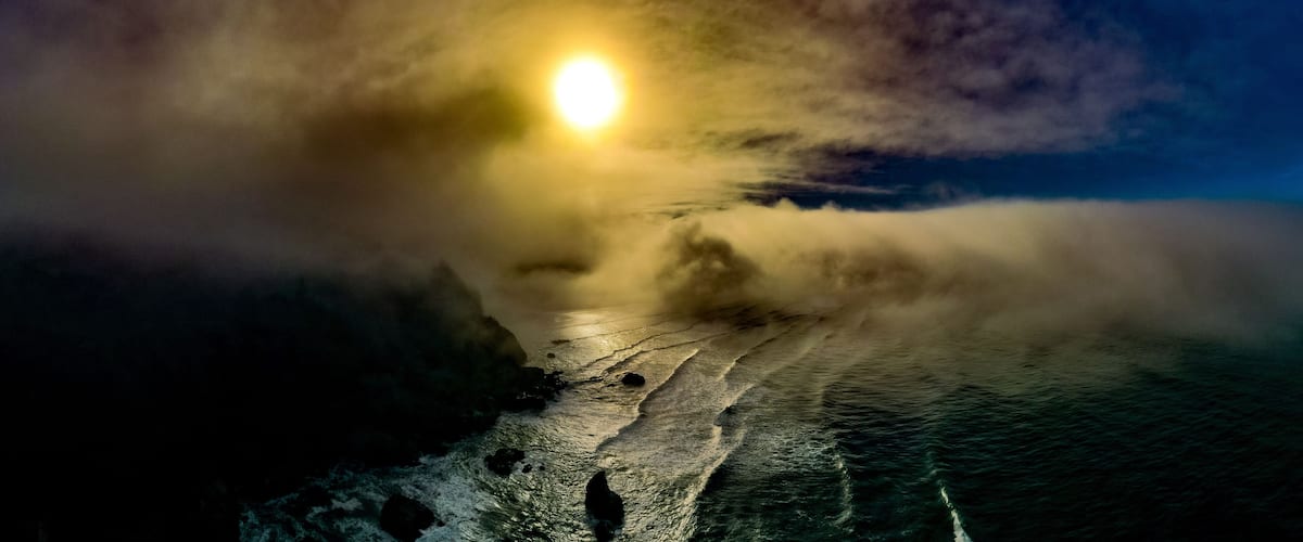 A moonlit ocean with waves crashing onto a rocky shore.