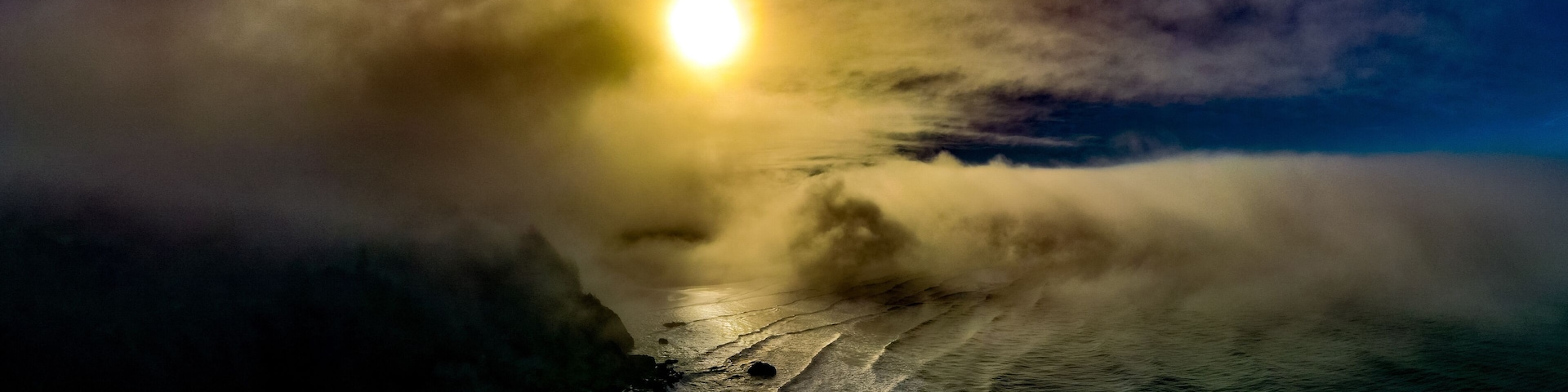 A moonlit ocean with waves crashing onto a rocky shore.