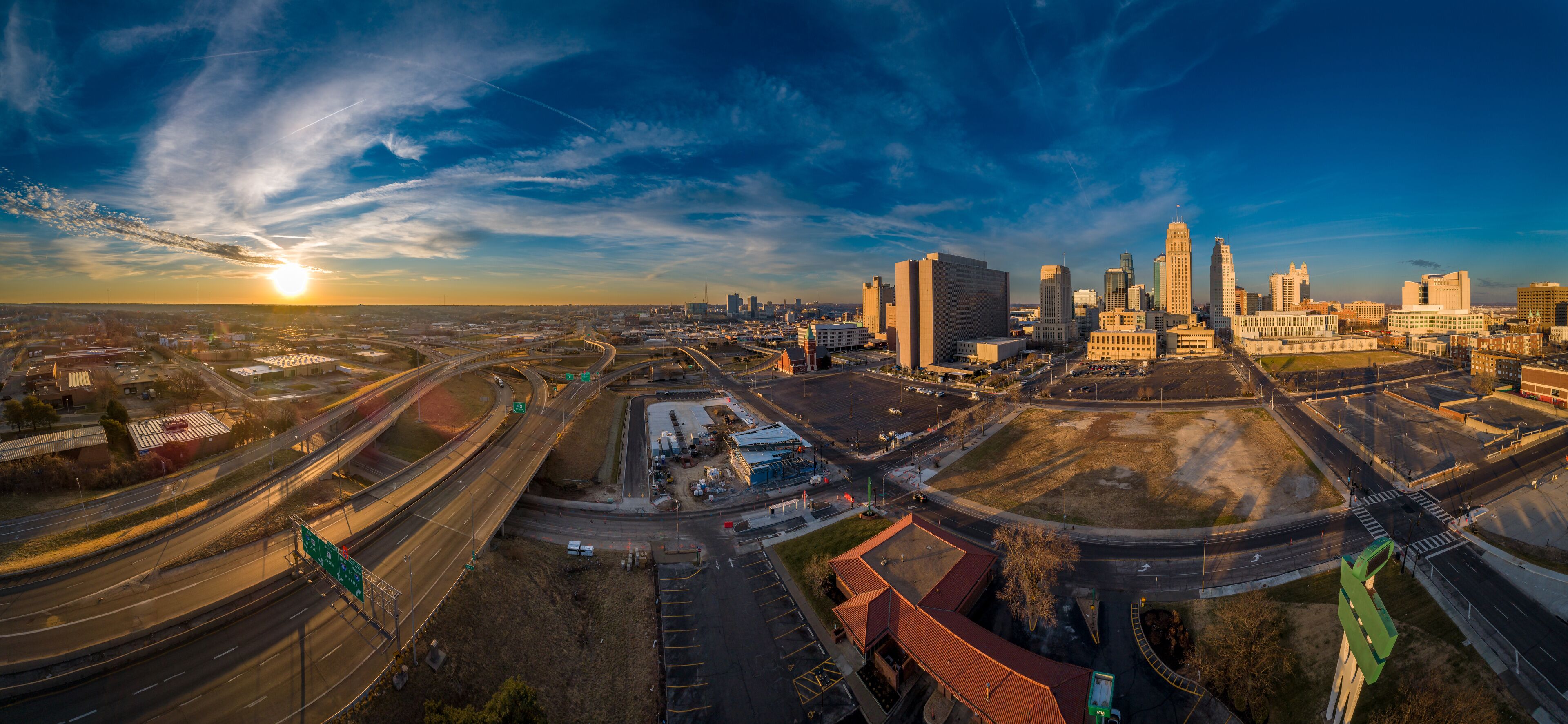 A cityscape with a prominent building complex, highways, and a sunset.