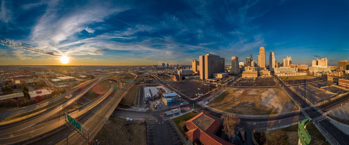 A cityscape with a prominent building complex, highways, and a sunset.