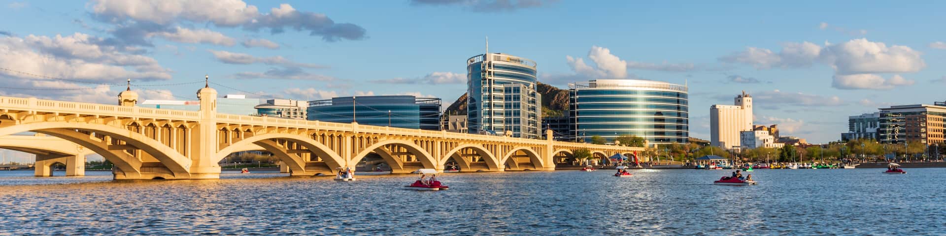 A river with a bridge, boats, and modern buildings in the background.