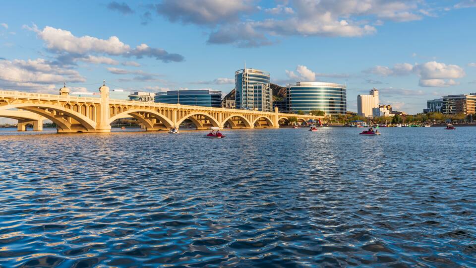 Un río con un puente, barcos y edificios modernos al fondo.