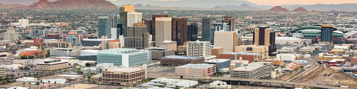 A cityscape with modern buildings, a bridge, and mountains in the background.