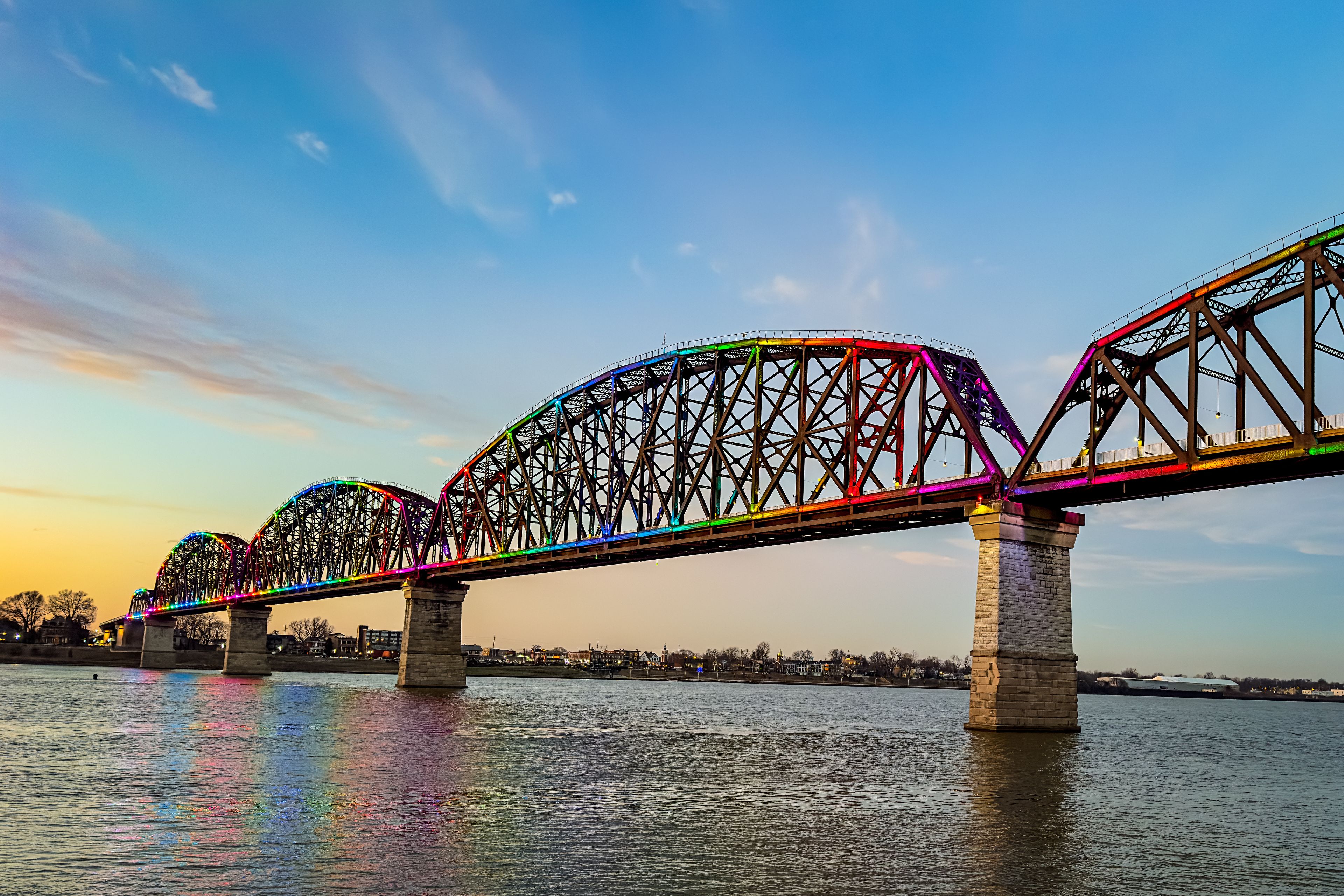 A multi-span bridge with colorful lights against a sunset sky.
