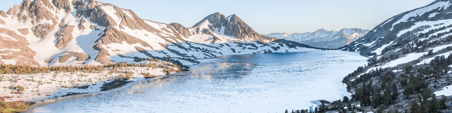 A glacial lake surrounded by rugged mountains and sparse forests.