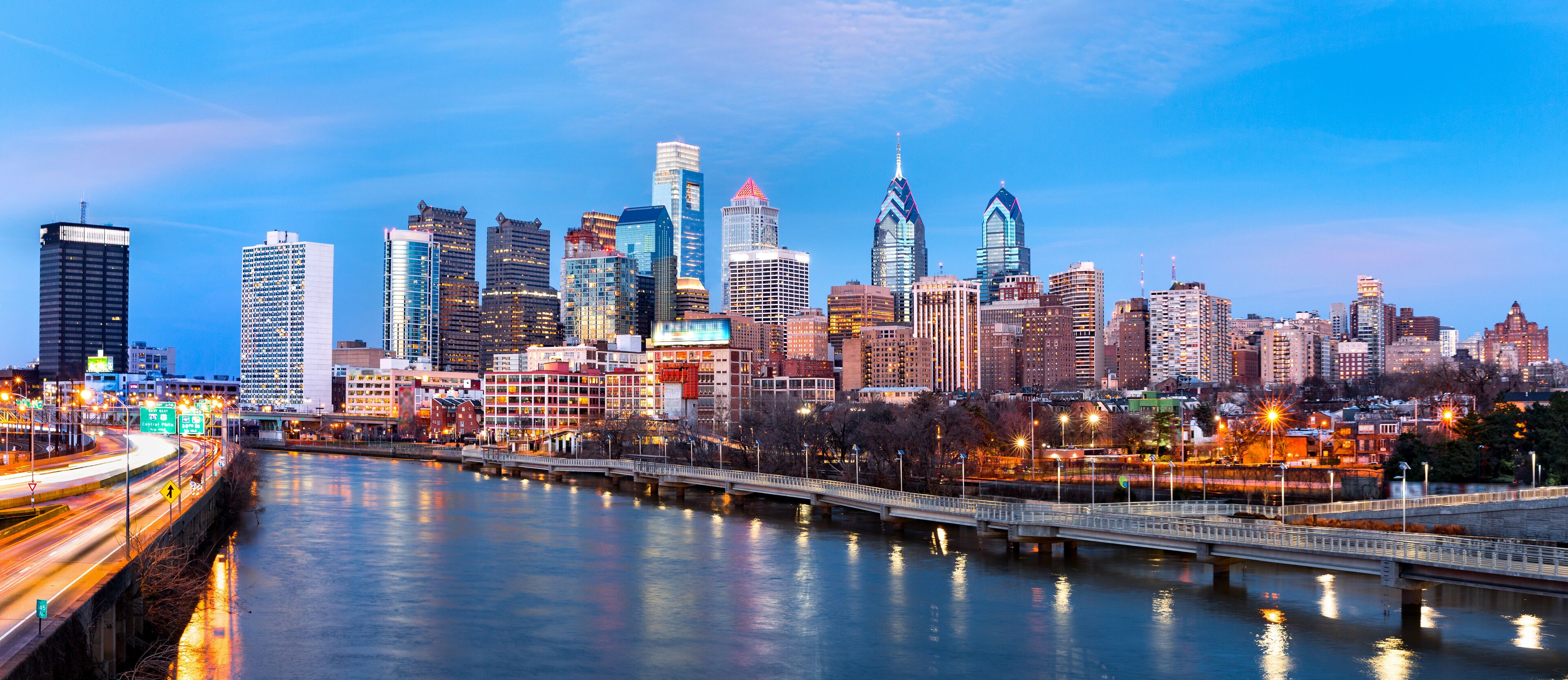 A city skyline with a river and a bridge.