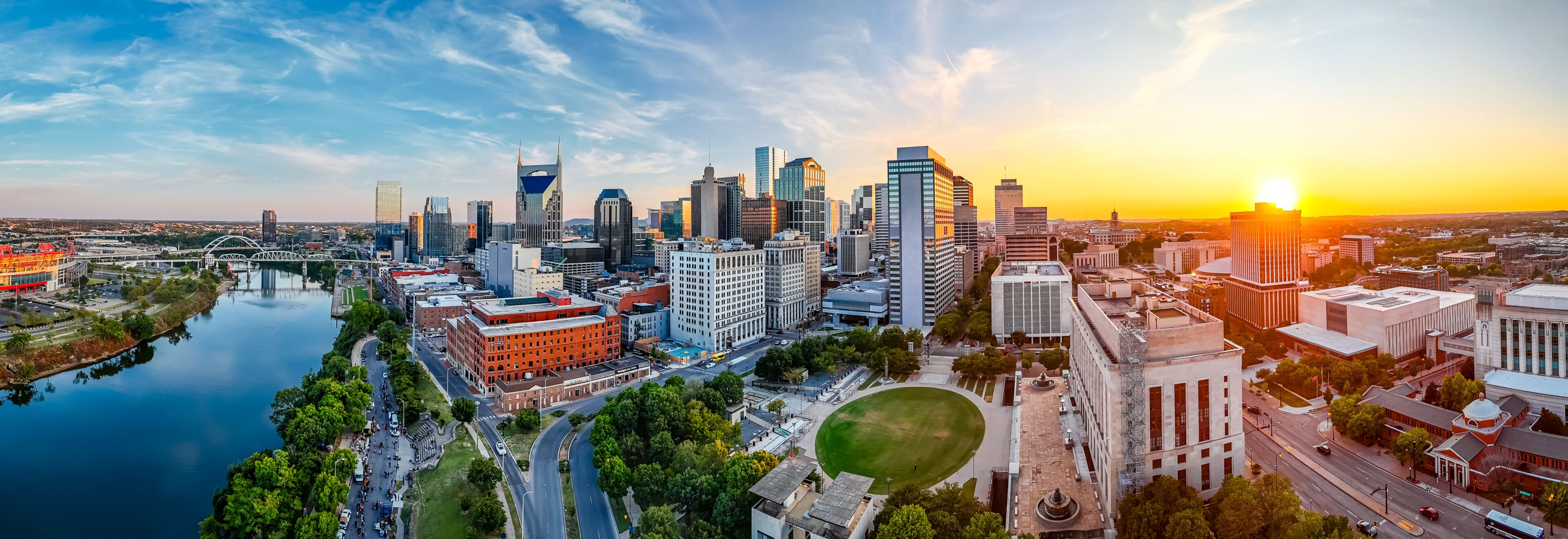 Panoramic view of Nashville skyline at sunset with river, skyscrapers, and city landmarks