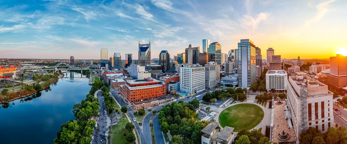 A city skyline with a river, modern buildings, and a bridge.