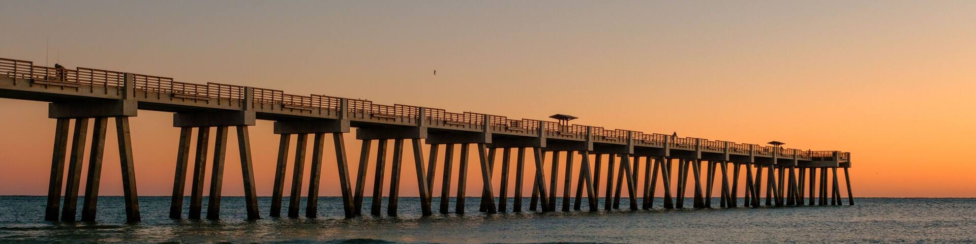 A pier extending into the ocean at sunset.