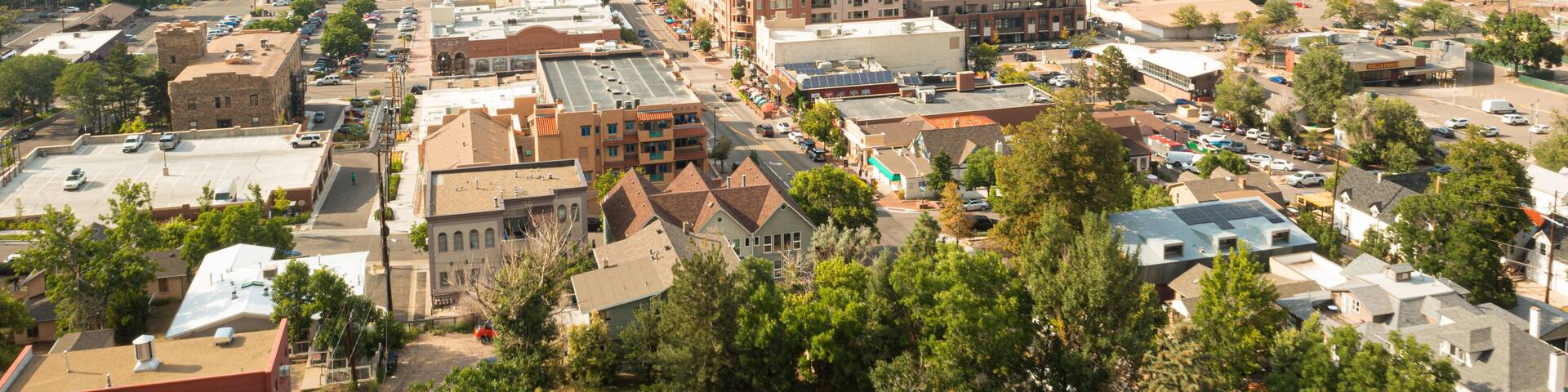 A town with a mix of modern and historic buildings, surrounded by green hills and mountains.