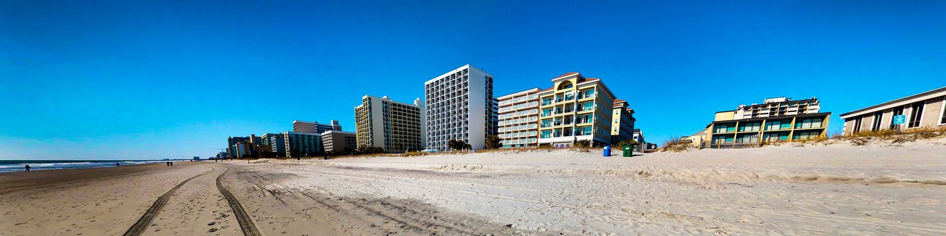 A beach with footprints leading to a building complex.