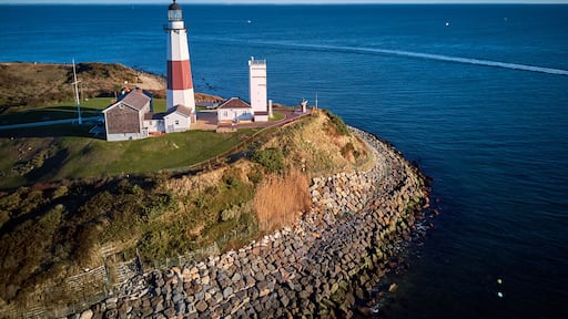 A lighthouse on a rocky coastline with a clear blue sky.