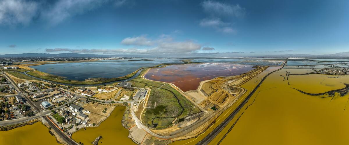 Aerial panorama view of Alviso district in San Jose California with rundown buildings colorful orange, yellow salt marshes in the Bay Area