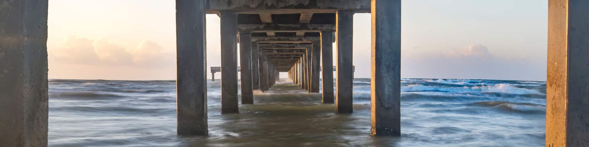 A pier extending into the ocean with waves crashing against the structure.