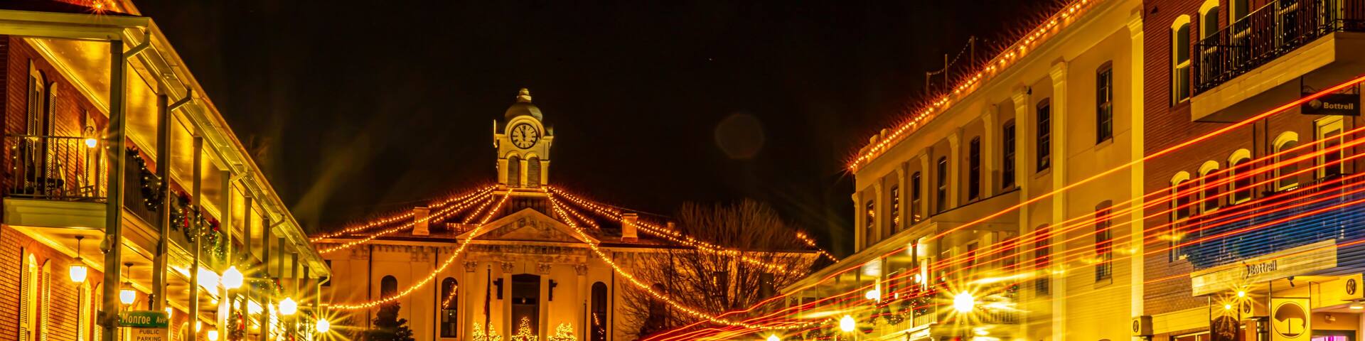 Historic Oxford Courthouse in the middle of town square with streaming head and tail lights at night. Christmas lights dominate.