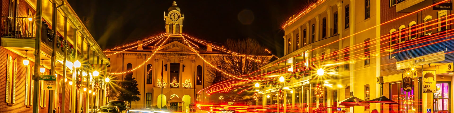 Historic Oxford Courthouse in the middle of town square with streaming head and tail lights at night. Christmas lights dominate.