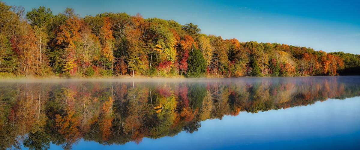 A calm lake reflecting autumn trees.