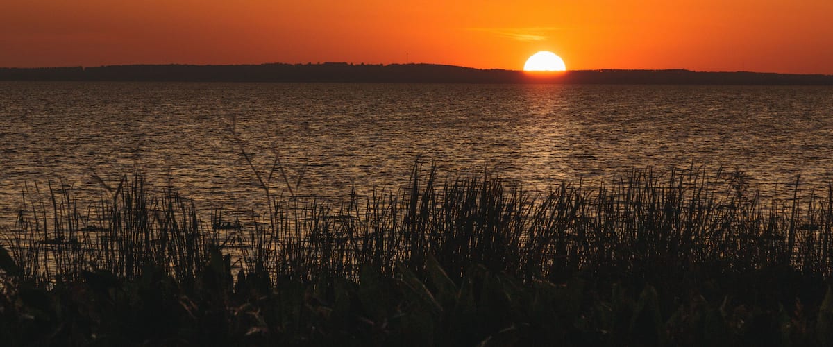 Orange sunset over distant hills on Lake Apopka near Orlando, Florida.