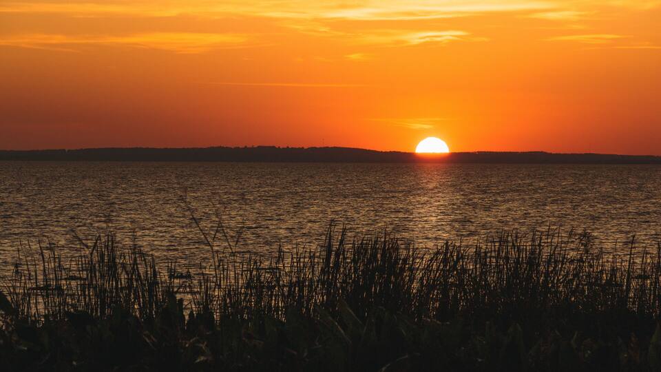 Orange sunset over distant hills on Lake Apopka near Orlando, Florida.
