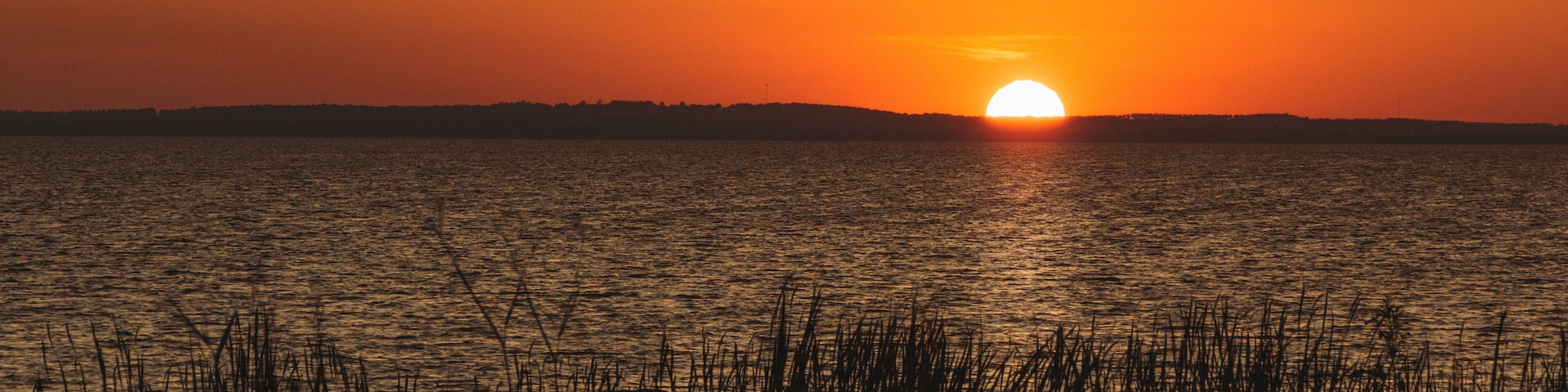 Orange sunset over distant hills on Lake Apopka near Orlando, Florida.