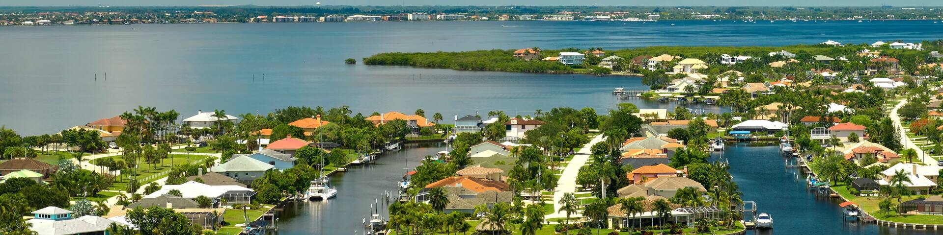 Aerial view of residential suburbs with private homes located on gulf coast near wildlife wetlands with green vegetation on sea shore.