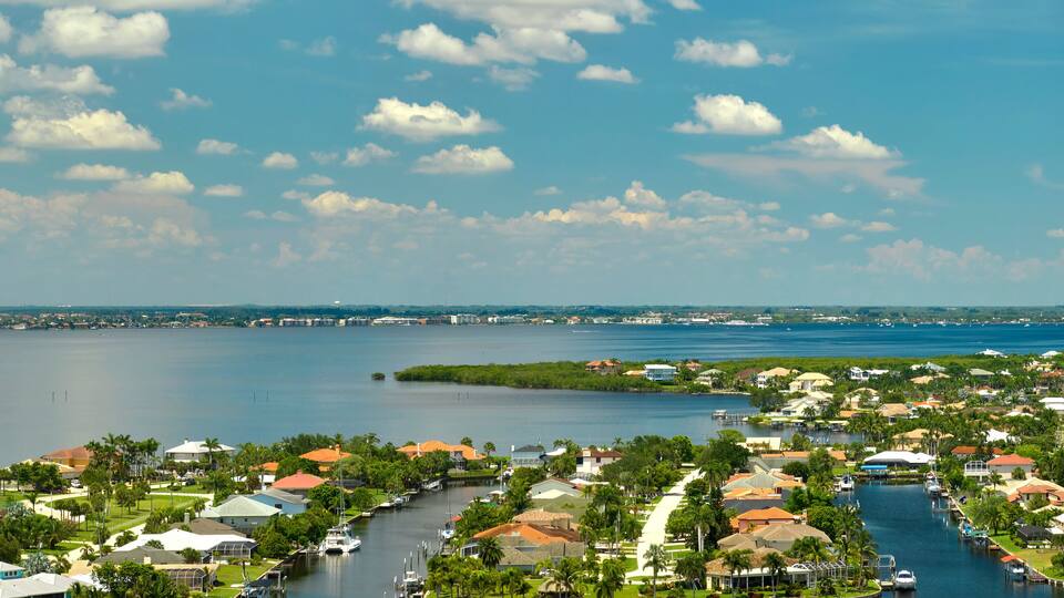 Aerial view of residential suburbs with private homes located on gulf coast near wildlife wetlands with green vegetation on sea shore.
