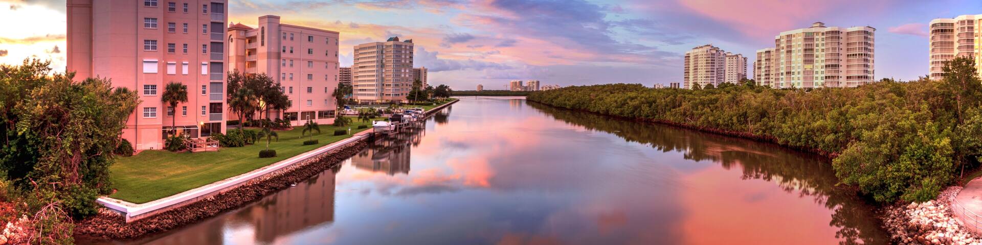 A river with buildings on both sides, a clear sky, and a sunset.