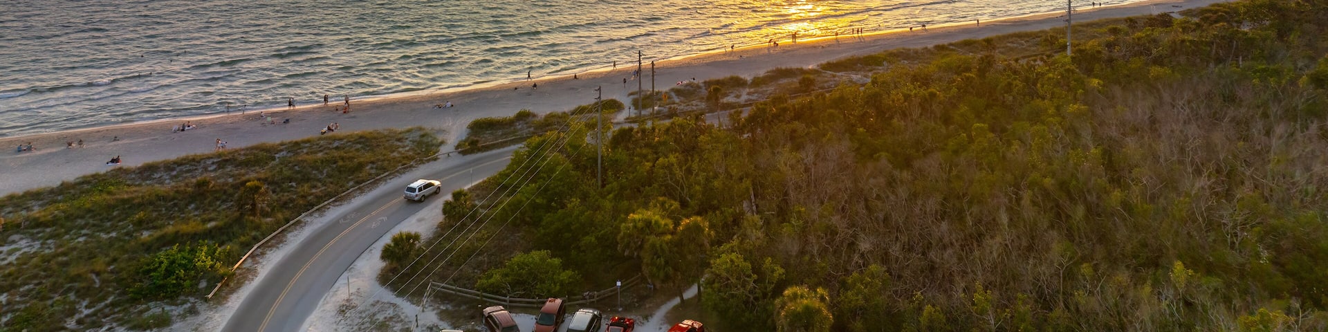 Parking lot at Blind Pass beach on Manasota Key in Englewood. Tourists cars in front of ocean beach with soft white sand in Florida. Popular vacation spot at sunset