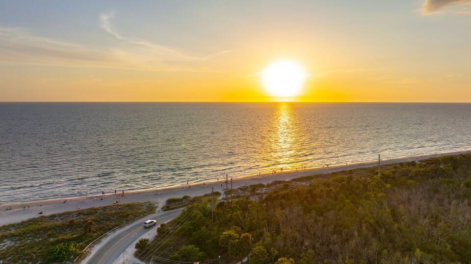 Parking lot at Blind Pass beach on Manasota Key in Englewood. Tourists cars in front of ocean beach with soft white sand in Florida. Popular vacation spot at sunset