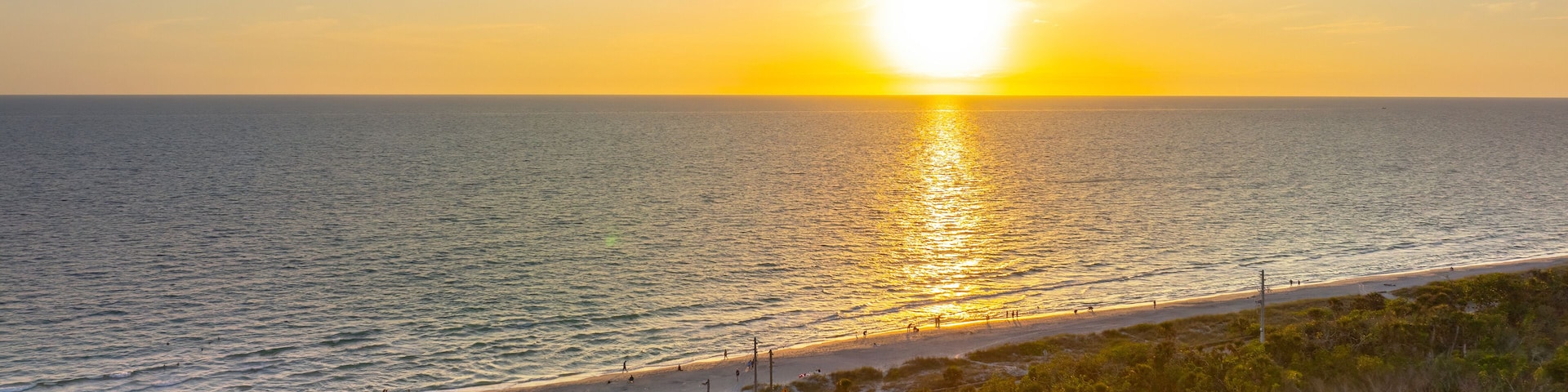 Parking lot at Blind Pass beach on Manasota Key in Englewood. Tourists cars in front of ocean beach with soft white sand in Florida. Popular vacation spot at sunset