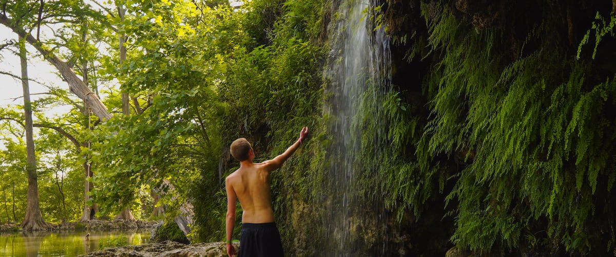 Man at a waterfall at Krause Springs, Texas