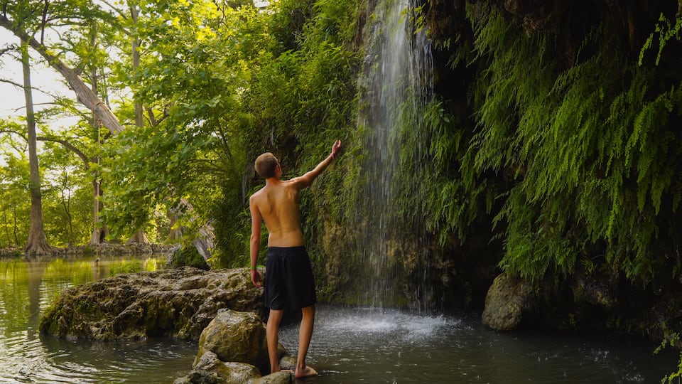 Man at a waterfall at Krause Springs, Texas