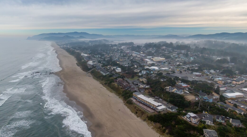 Coastal town of Lincoln City shrouded in fog, waves crashing on the beach, hotels and homes line the shore. Aerial view of a misty morning. Oceanlake, Oregon, USA