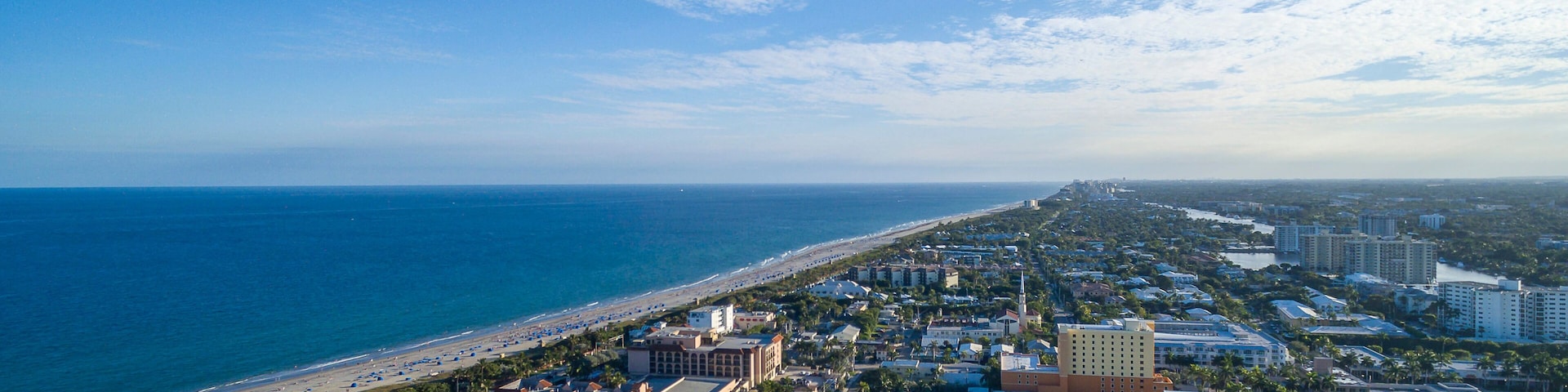 Eine Küstenstadt mit Strand, Wohnhäusern und blauem Himmel.