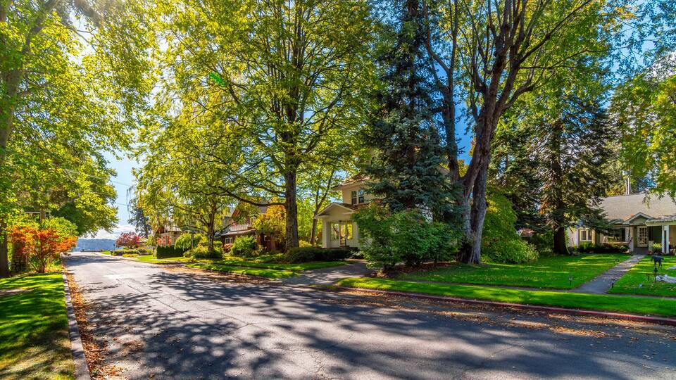 A shaded tree lined street of Victorian and historic homes across from the city park with the lake in view in historic Fort Grounds district of Coeur d'Alene, Idaho, USA.