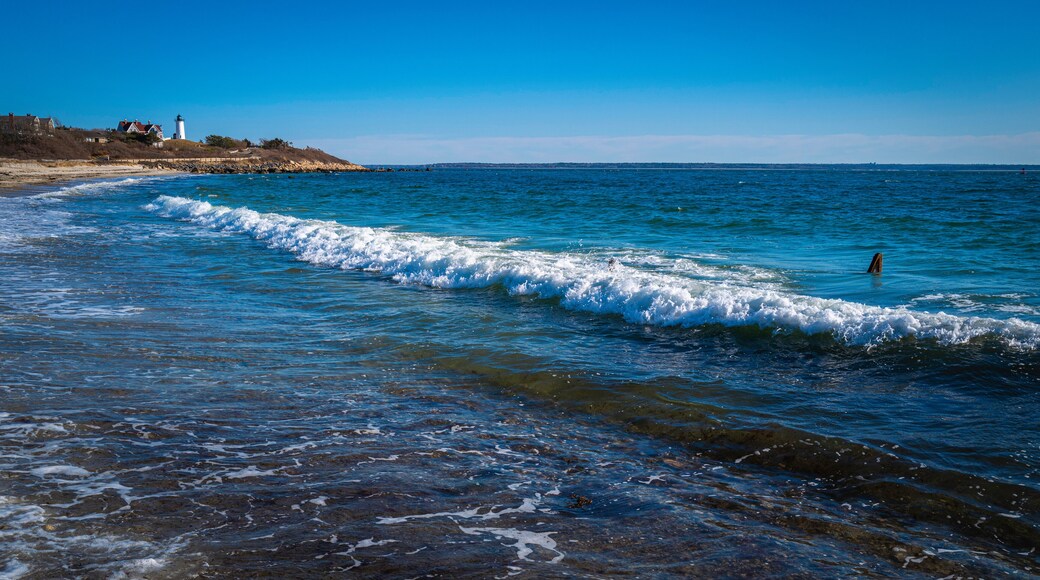 White waves rolling in diagonally on the rocky beach at Knobska Lighthouse beach on Cape Cod.