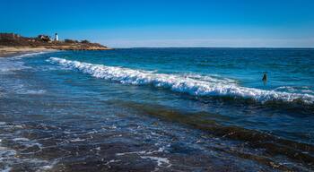 White waves rolling in diagonally on the rocky beach at Knobska Lighthouse beach on Cape Cod.