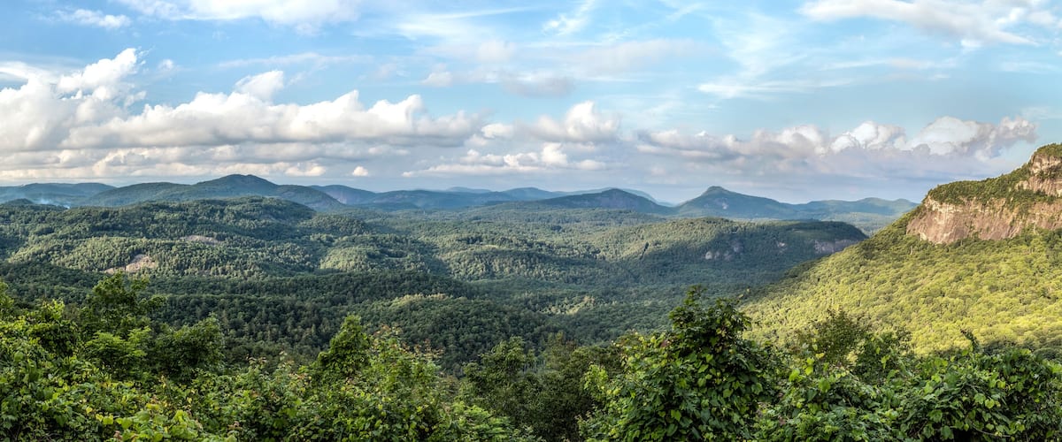 Sunlight dapples the vista from the Big View Scenic Overlook along Highway 64 between Cashiers and Highlands, North Carolina in Nantahala National Forest. Whiteside Mountain is to the right.