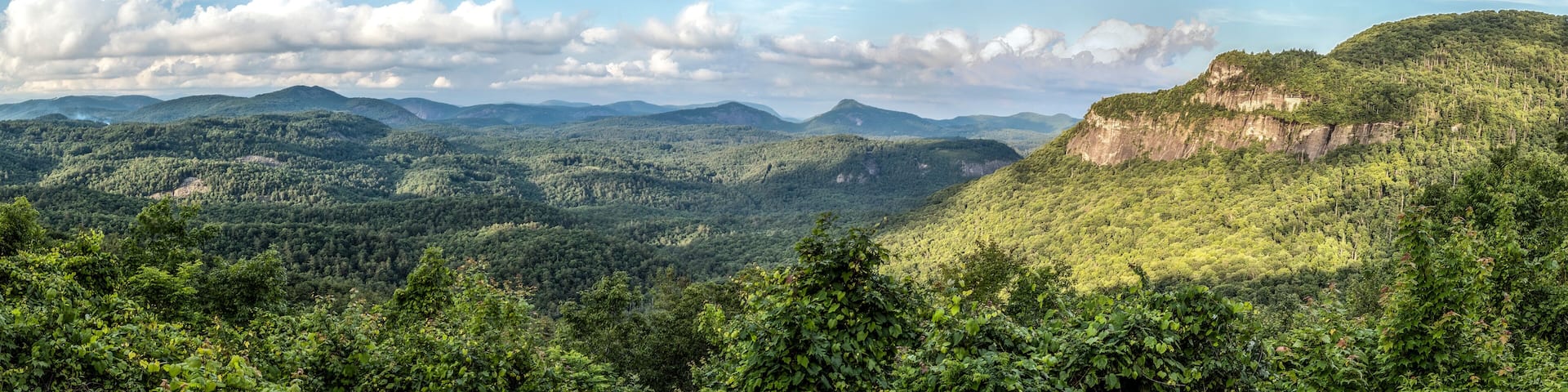 Sunlight dapples the vista from the Big View Scenic Overlook along Highway 64 between Cashiers and Highlands, North Carolina in Nantahala National Forest. Whiteside Mountain is to the right.
