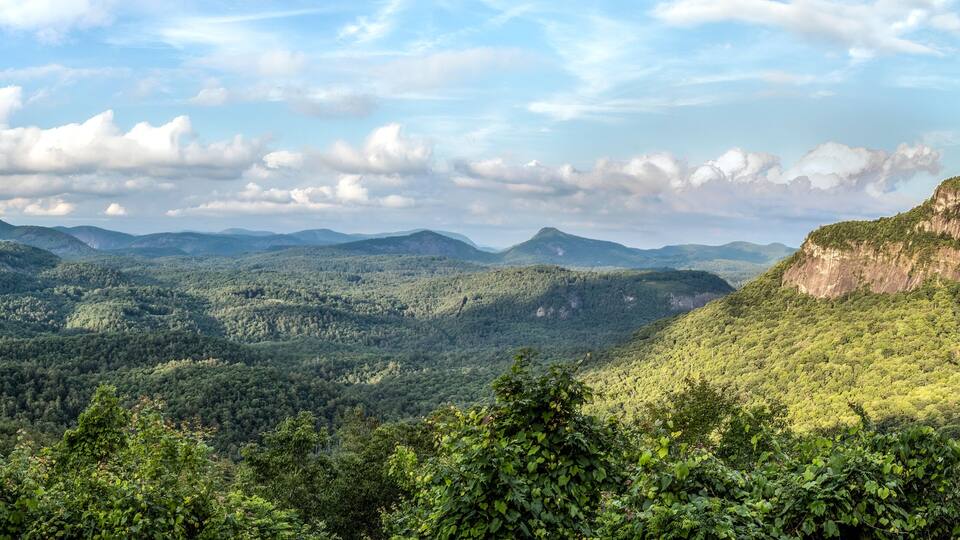 Sunlight dapples the vista from the Big View Scenic Overlook along Highway 64 between Cashiers and Highlands, North Carolina in Nantahala National Forest. Whiteside Mountain is to the right.