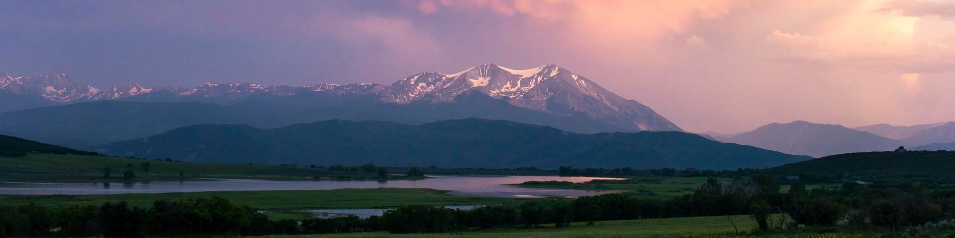 Scenic view of landscape against cloudy sky during sunset