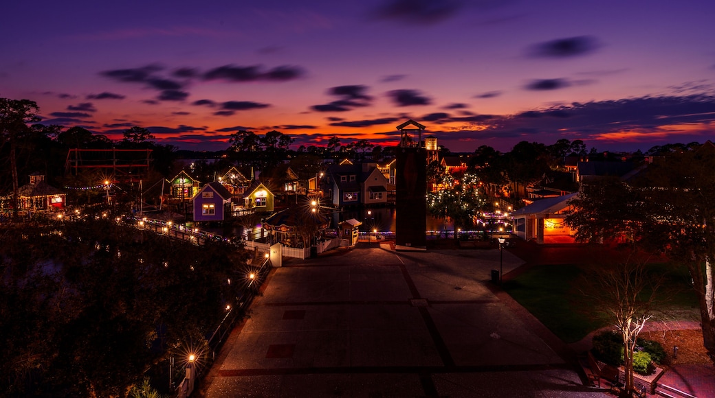Eine Stadt im Abenddämmerung mit beleuchteten Gebäuden und einem markanten Kirchturm.