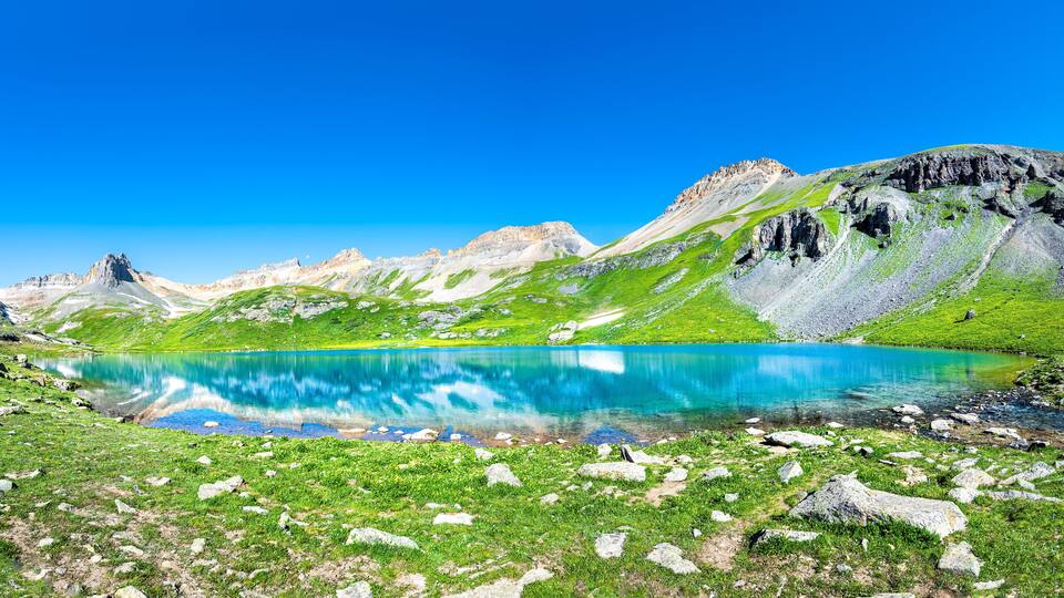 Panoramic view of beautiful Ice lake near Silverton, Colorado on rocky mountain peak and panorama reflection of summer landscape with nobody and green grass blue sky