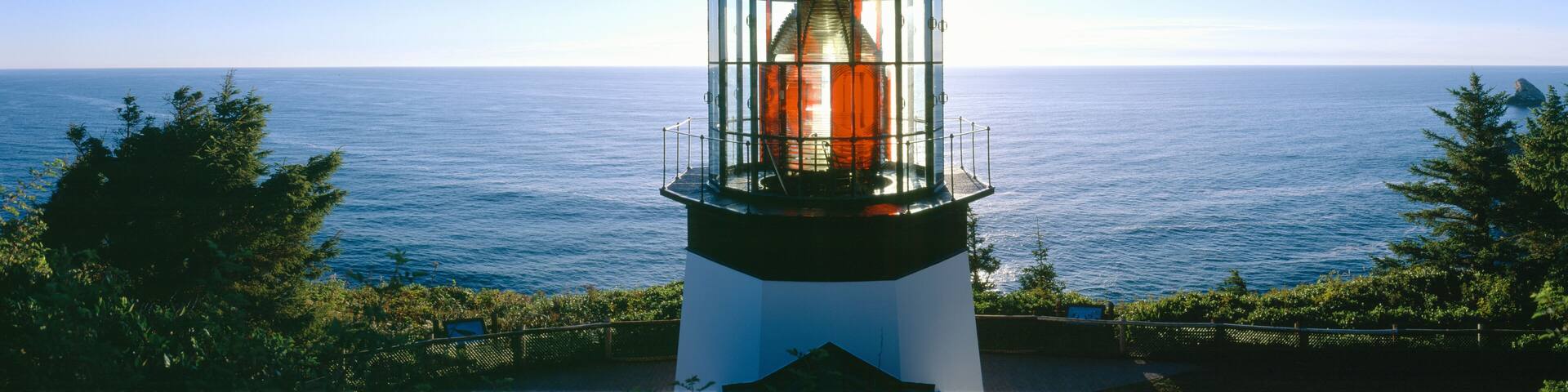 A lighthouse with a glass enclosure, overlooking a vast ocean.