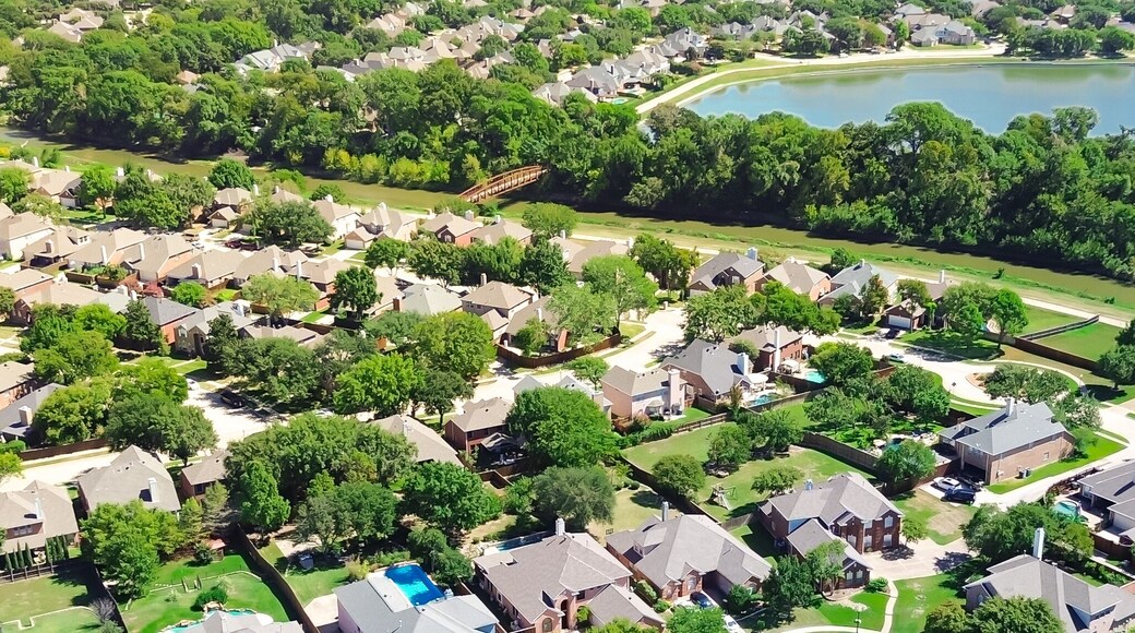 Panorama aerial view creek with bridge across residential neighborhood lush green suburban park lake, walking biking path, upscale new development two story houses swimming pools in Coppell Texas