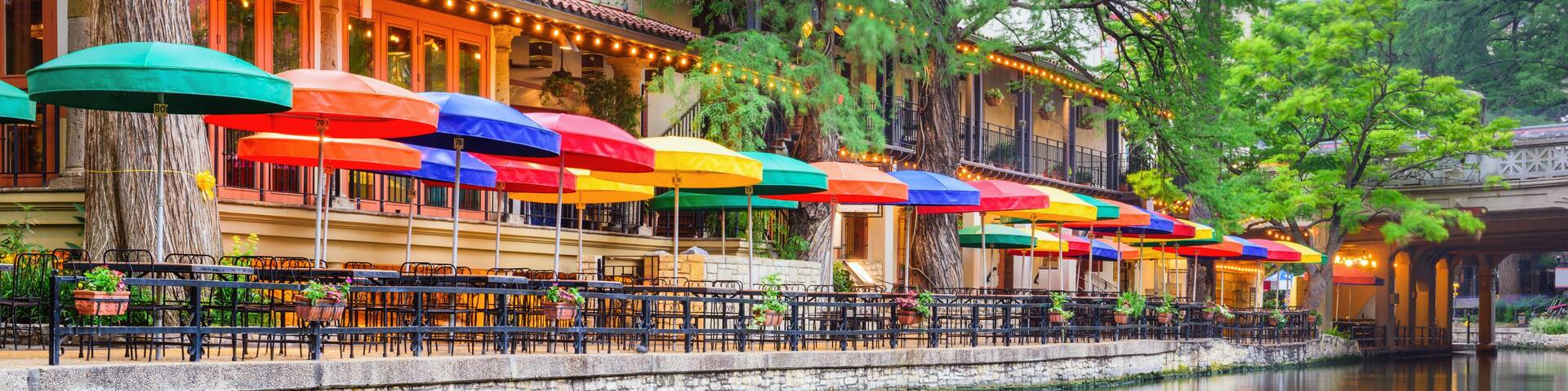 A riverside café with colorful umbrellas and outdoor seating.
