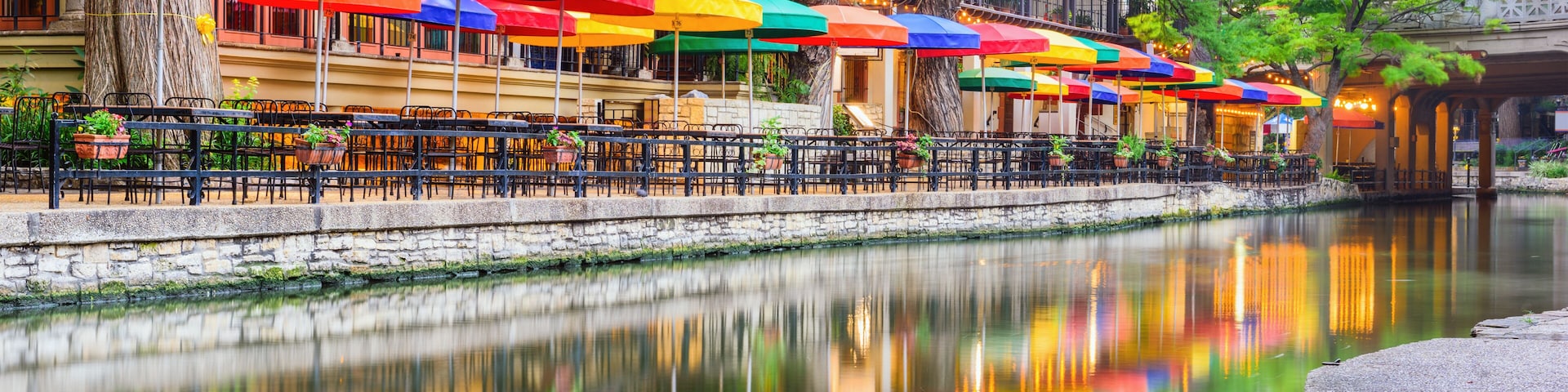 Un café situé au bord de la rivière, avec des parasols colorés et des tables en plein air.