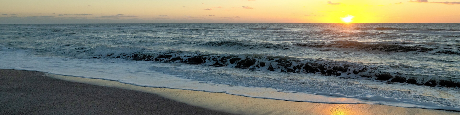 A dark yet colorful sunset over the ocean during the winter months of the West Coast of Florida beaches at sun set. Venice Florida calm and peaceful landscape of the sea with clear sky and sunny.