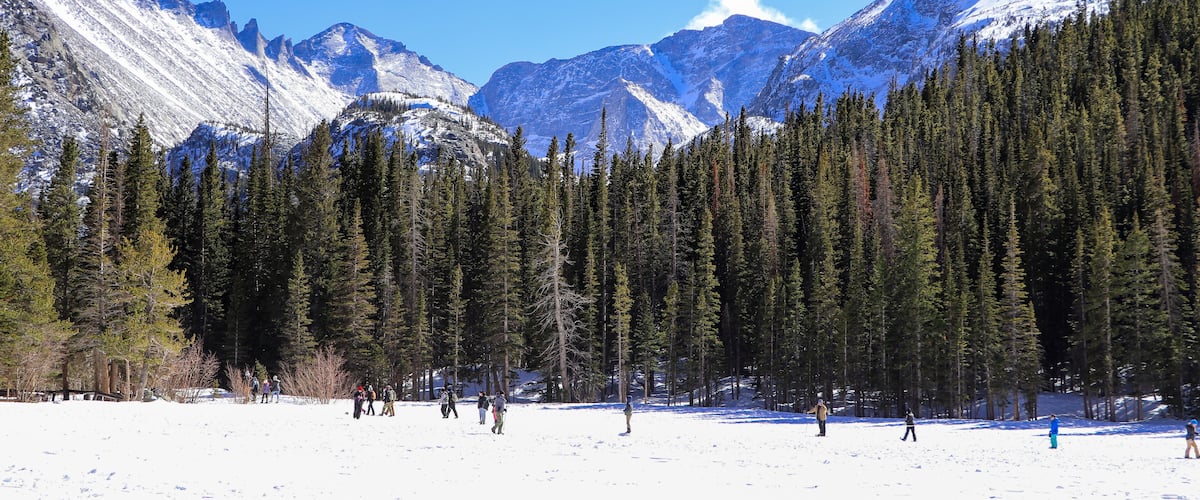 Frozen Bear Lake in Rocky Mountain National Park looking south. Hikers crossing the frozen lake on a cold March day.